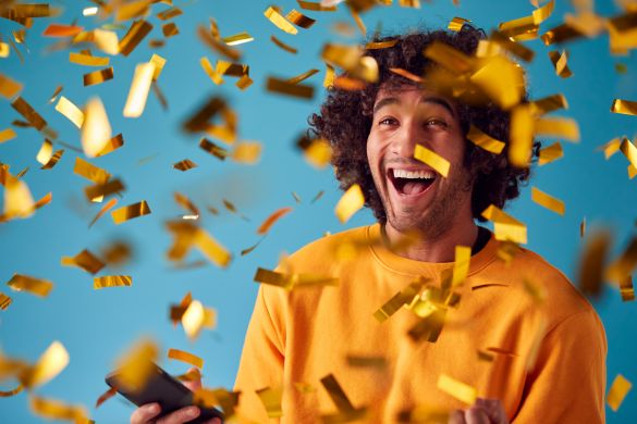 Man with mobile phone winning prize with gold confetti