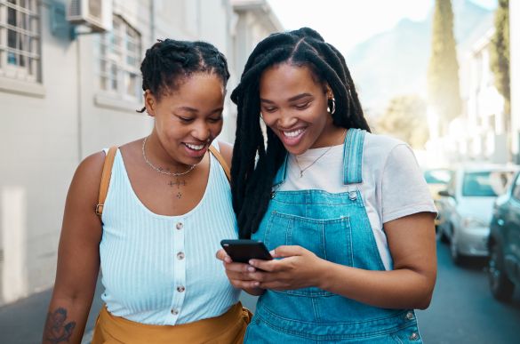 Two happy young women looking at a mobile device